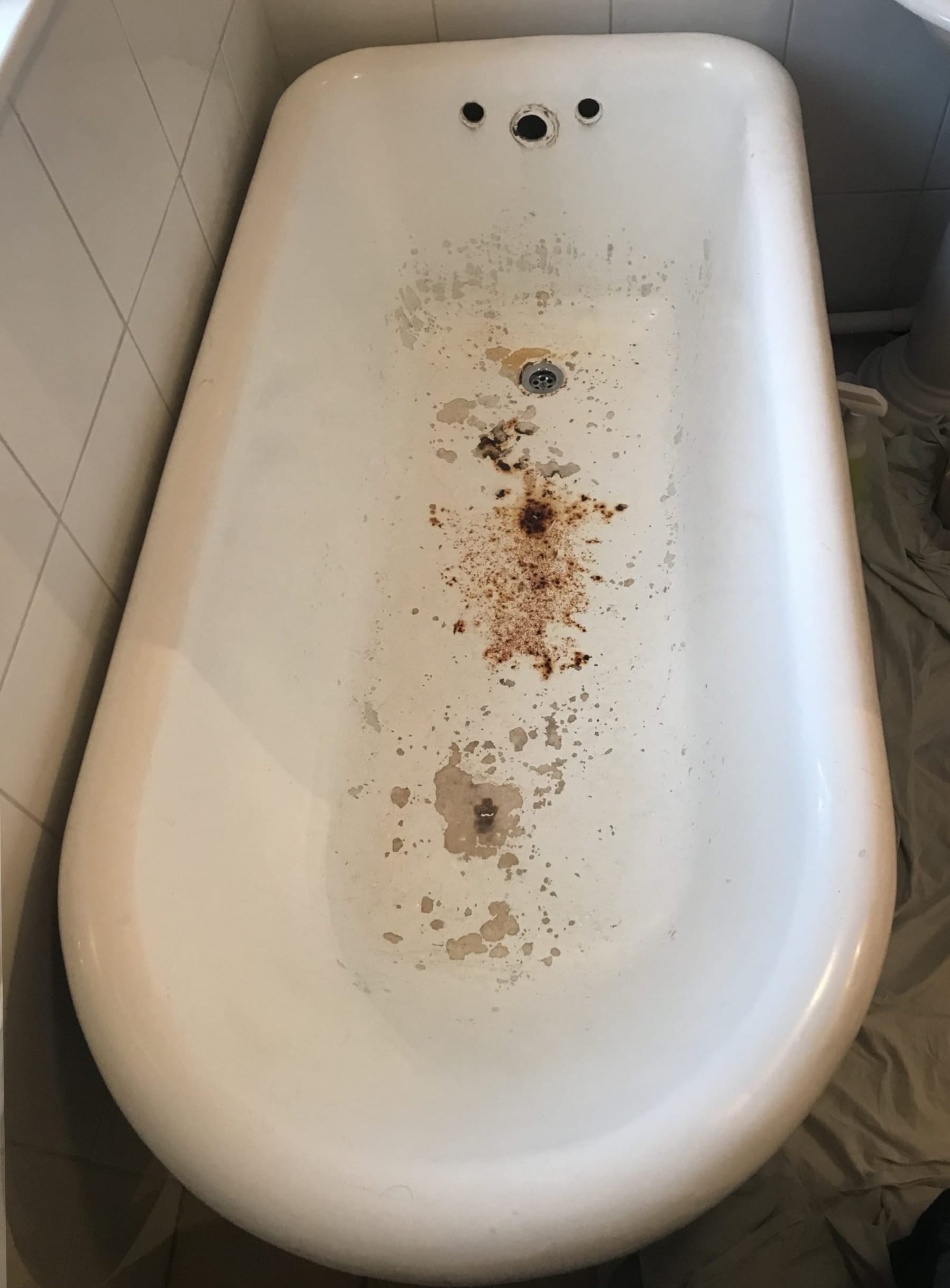 Roll top bath before resurfacing, with brown staining and a worn, rough surface