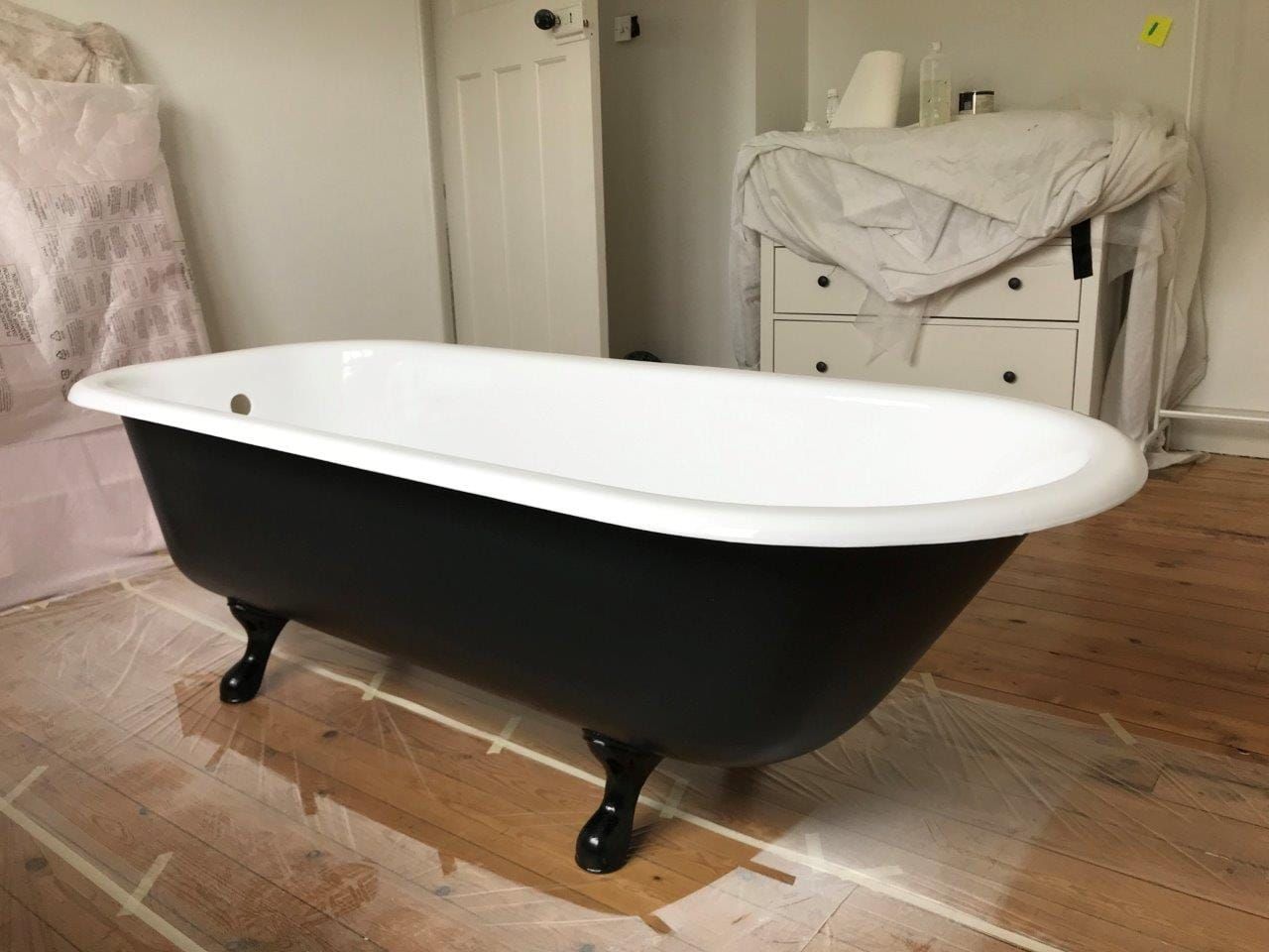 Freestanding bath with a black exterior and white interior in a bedroom