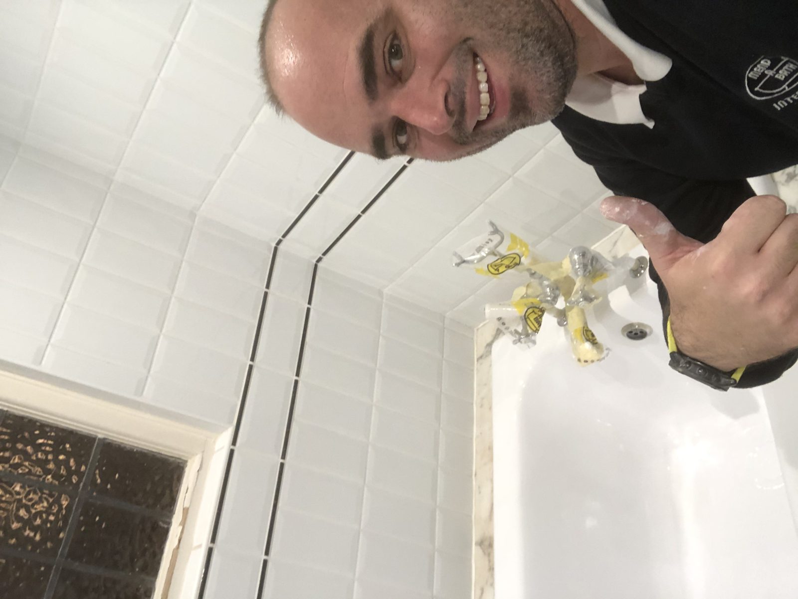 Smiling Mendabath technician on site beside a bath being restored